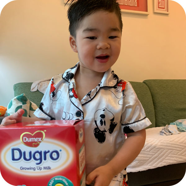 Little boy with a box of Dugro Growing Up Formula Milk