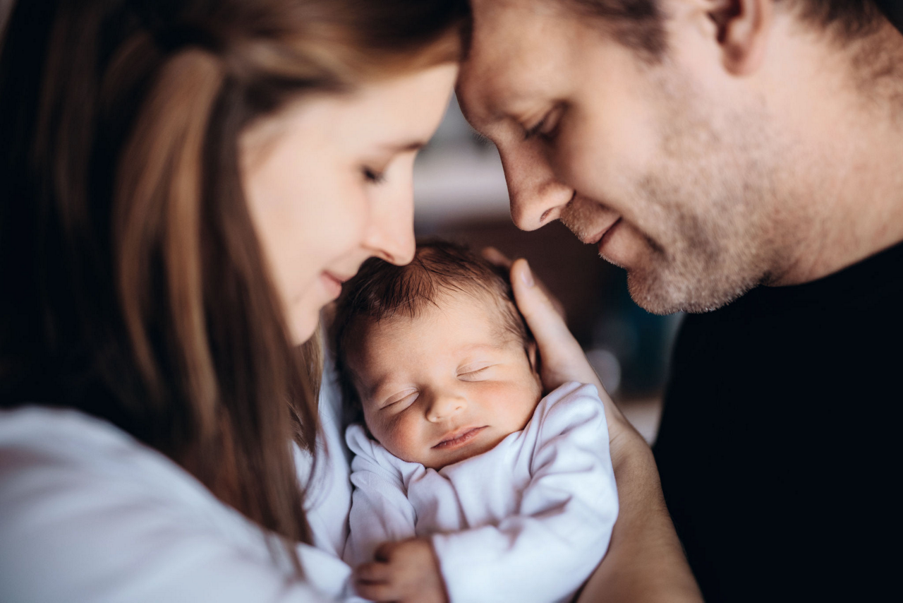A  young woman and man looking at their new baby boy or girl with love.