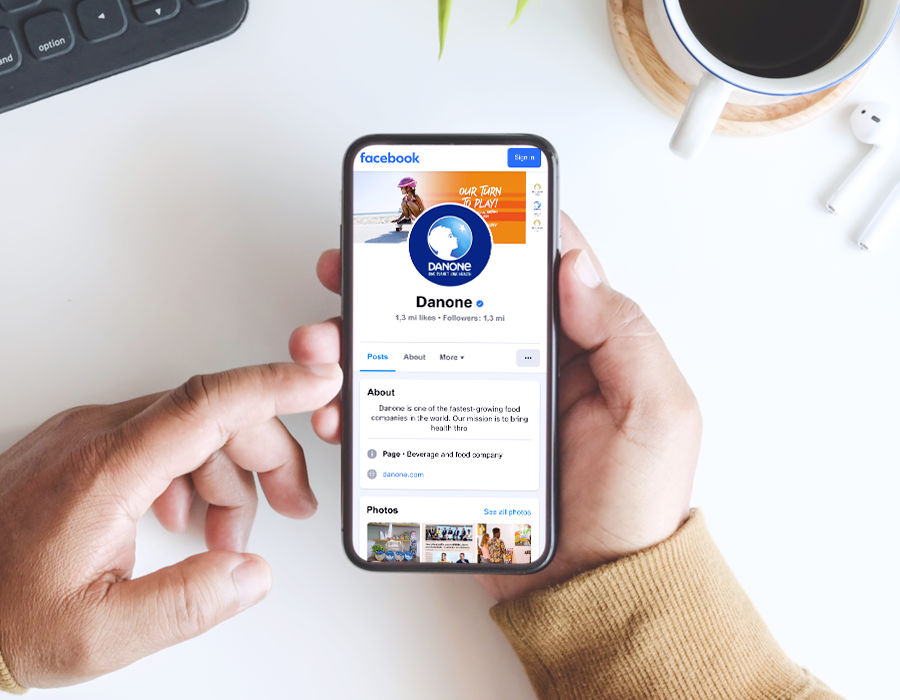 A hand holding a smartphone displaying Danone Canada's LinkedIn profile.