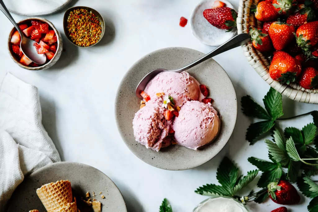 Directly above shot of strawberry ice cream in a bowl on table. Freshly made strawberry ice-cream on table with ingredients around.