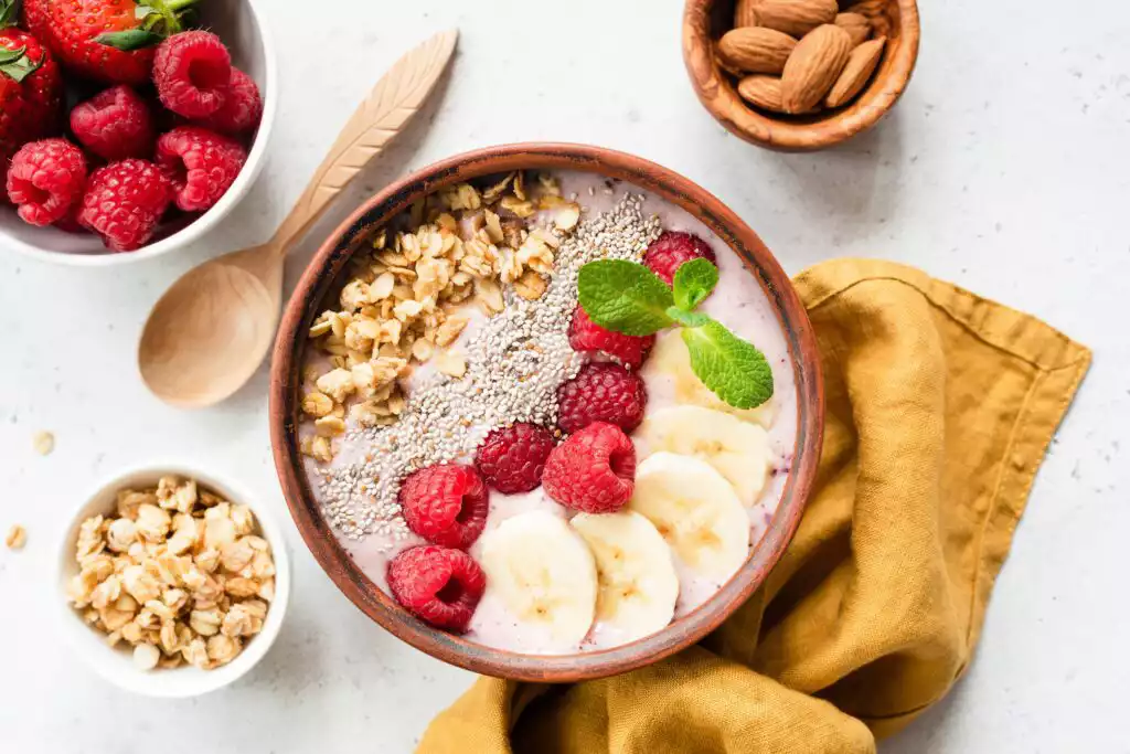 Acai smoothie bowl with superfood. Fruit smoothie with banana, raspberry, chia seed and granola in coconut bowl, top view