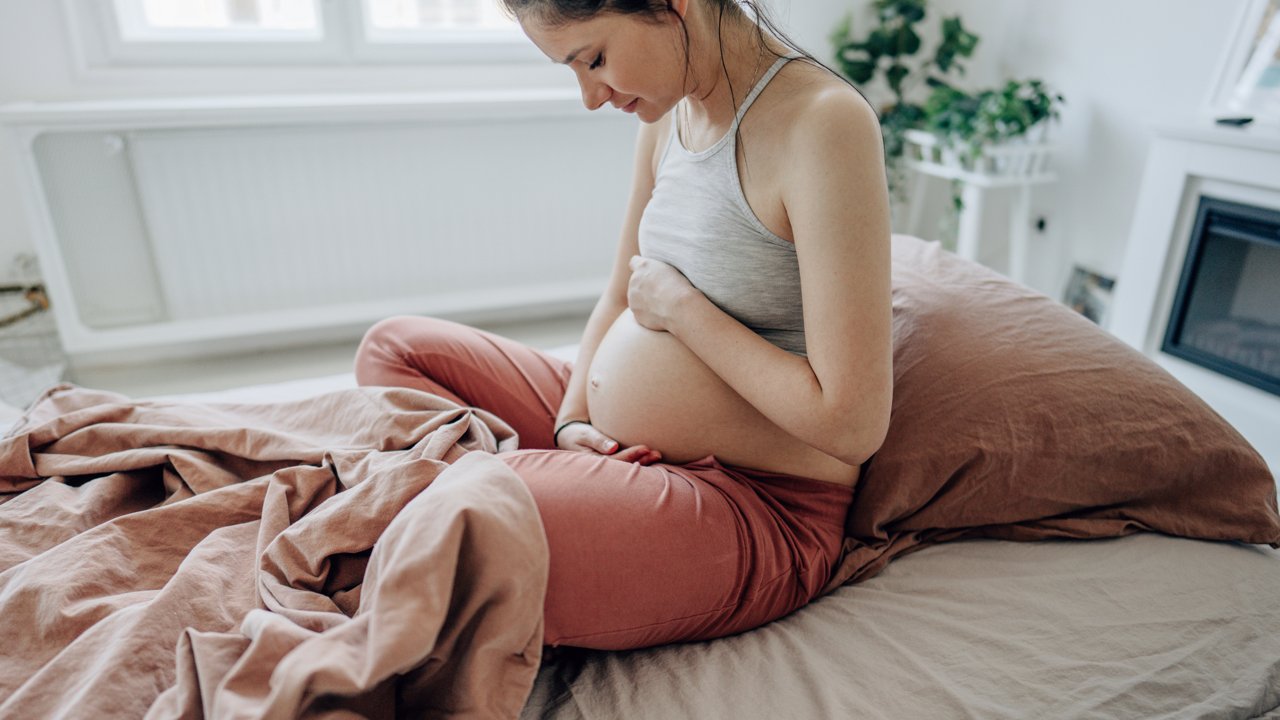 Frau mit Babybauch im Bett