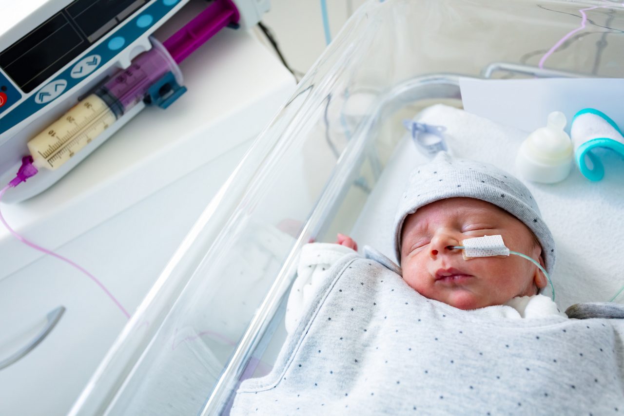 Premature newborn baby and syringe with pump machine pumping milk, NUCU ward at the hospital getty images 1209858302