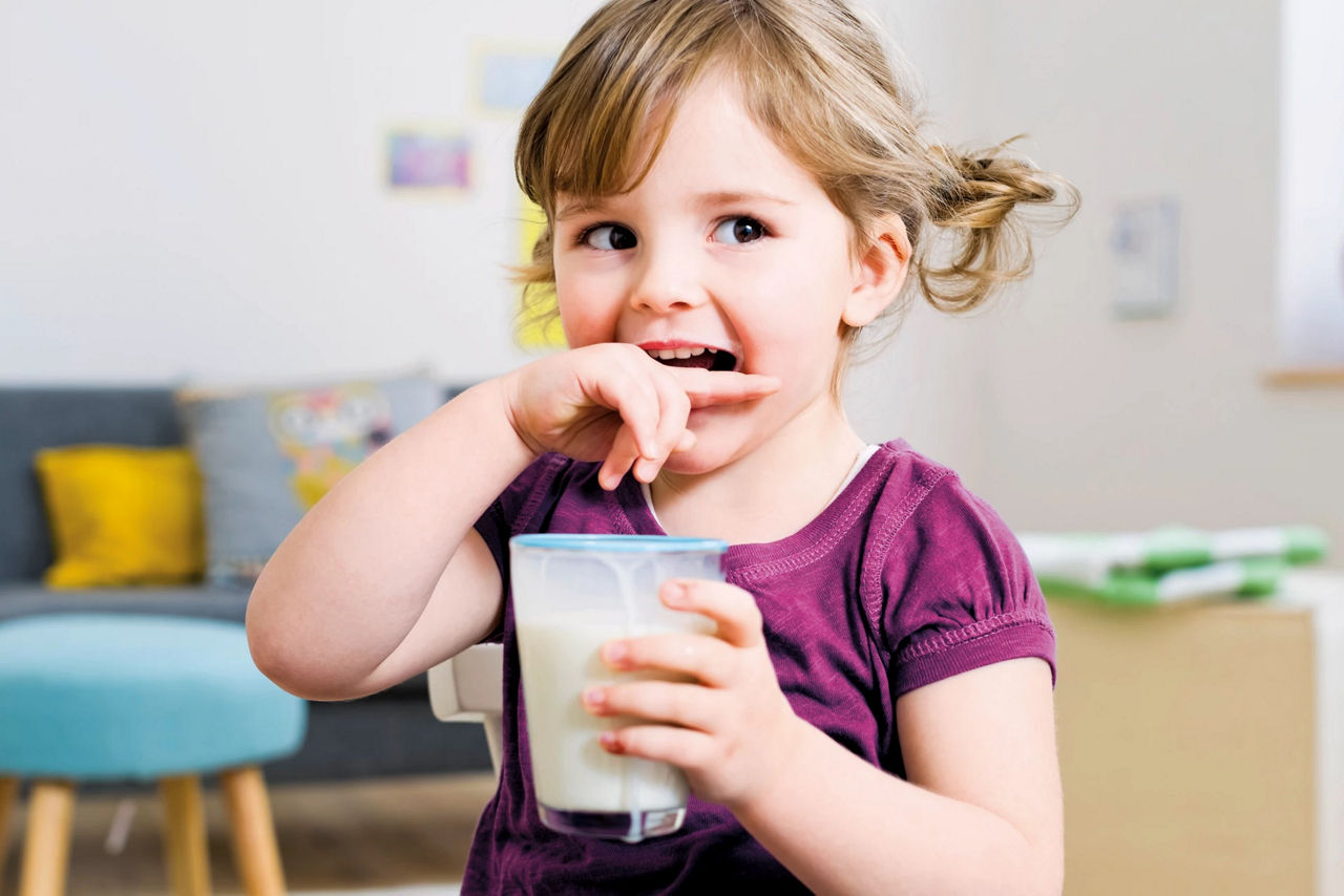 Girl toddler biting her finger milk
