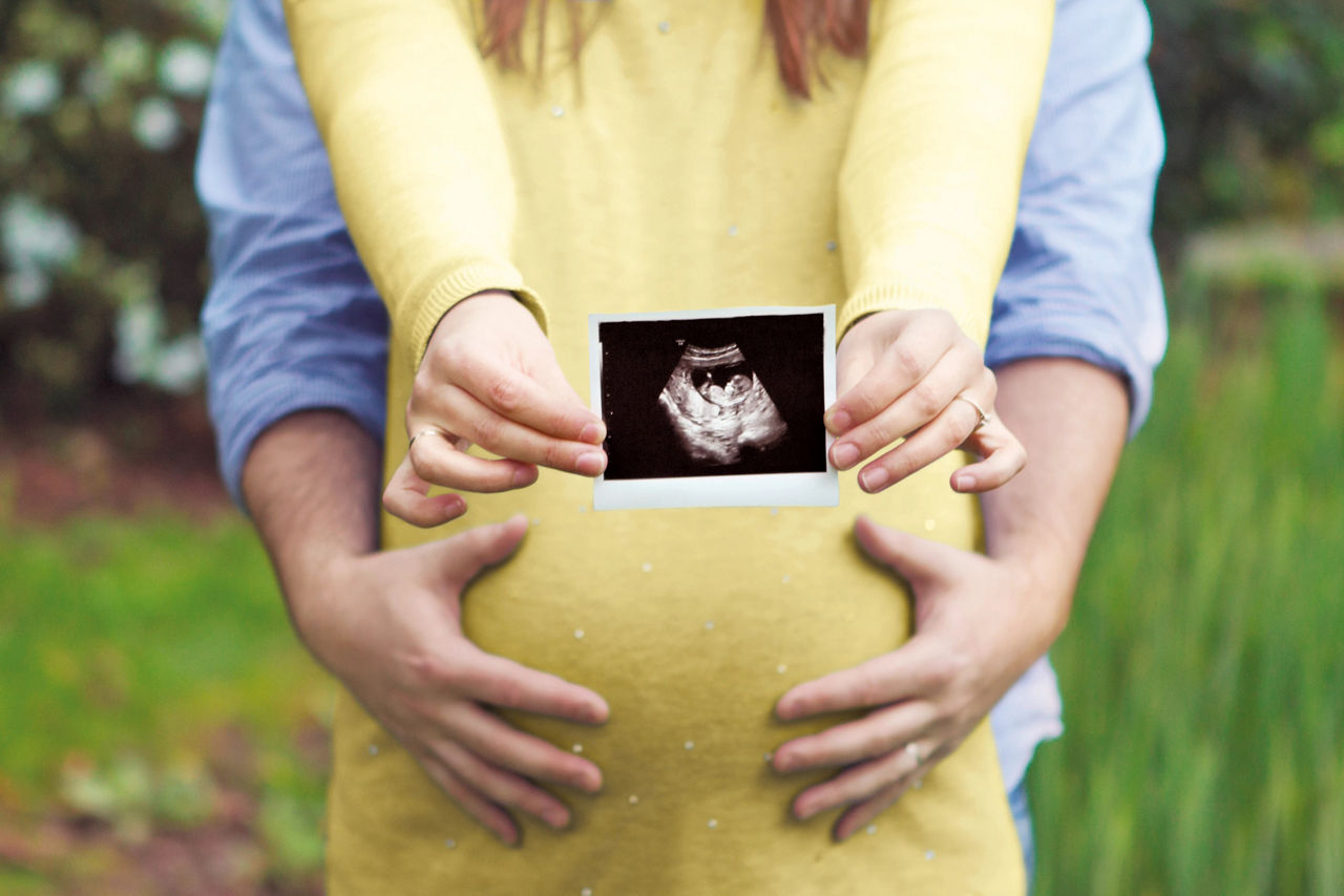 Pregnant couple holding screening image