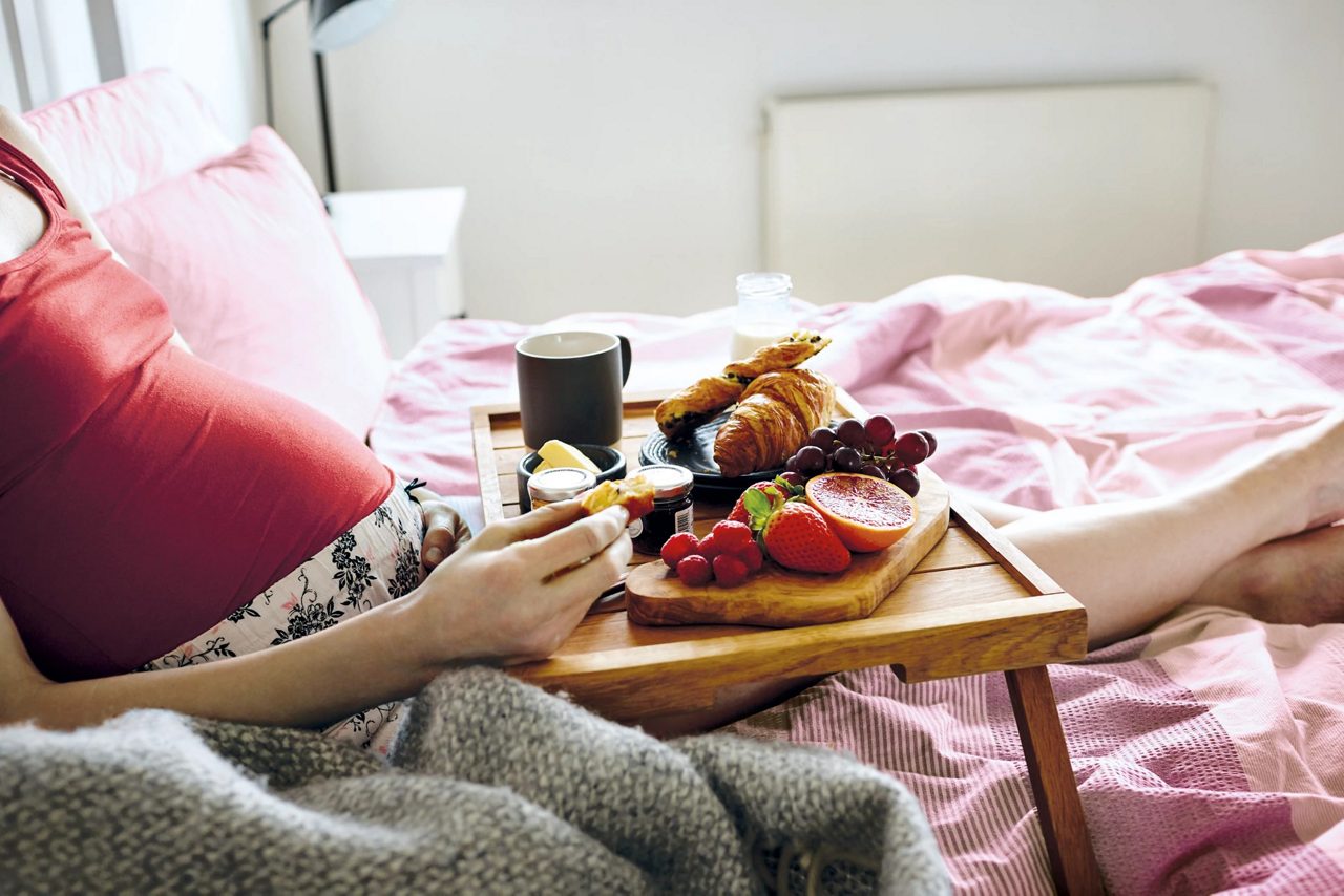Pregnant woman having breakfast in bed