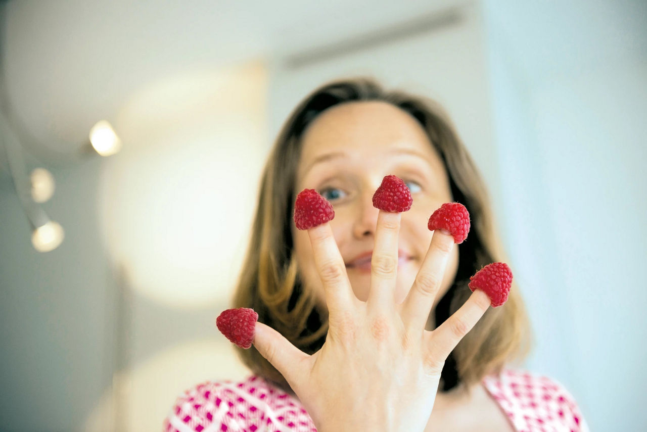 Woman holding raspberries in her hand