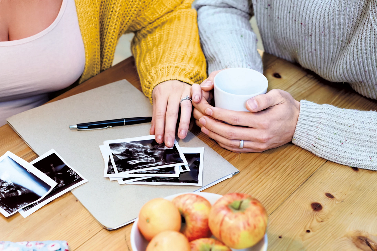 pregnant parent at table with scan pictures