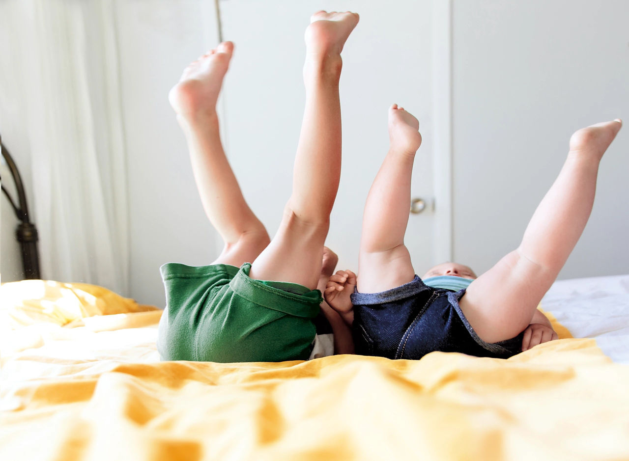 Baby and toddler on a bed