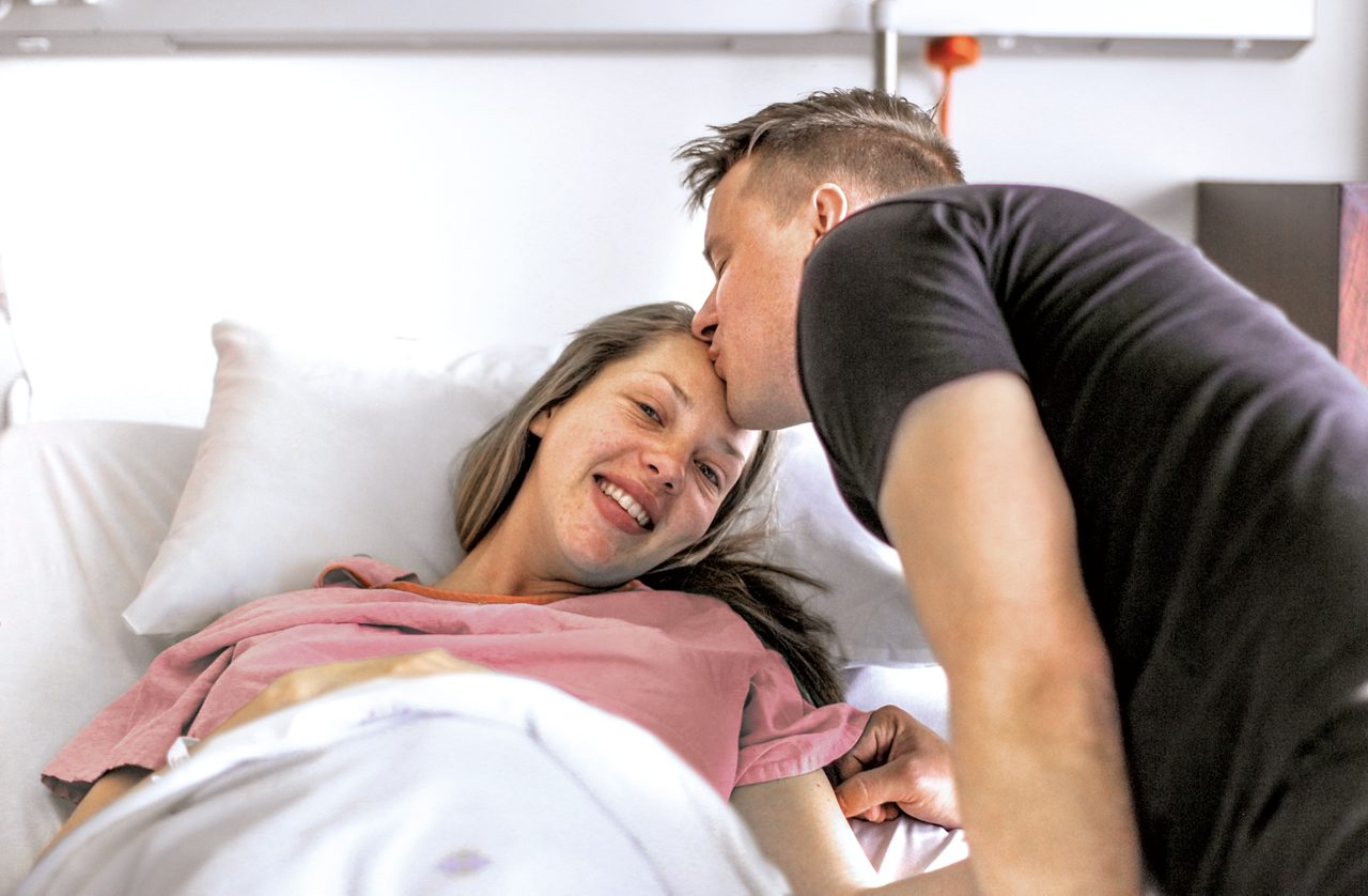 Dad kissing mums forehead in hospital