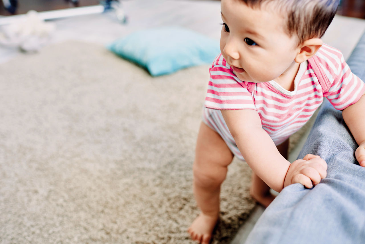 Baby holding onto sofa walking first steps