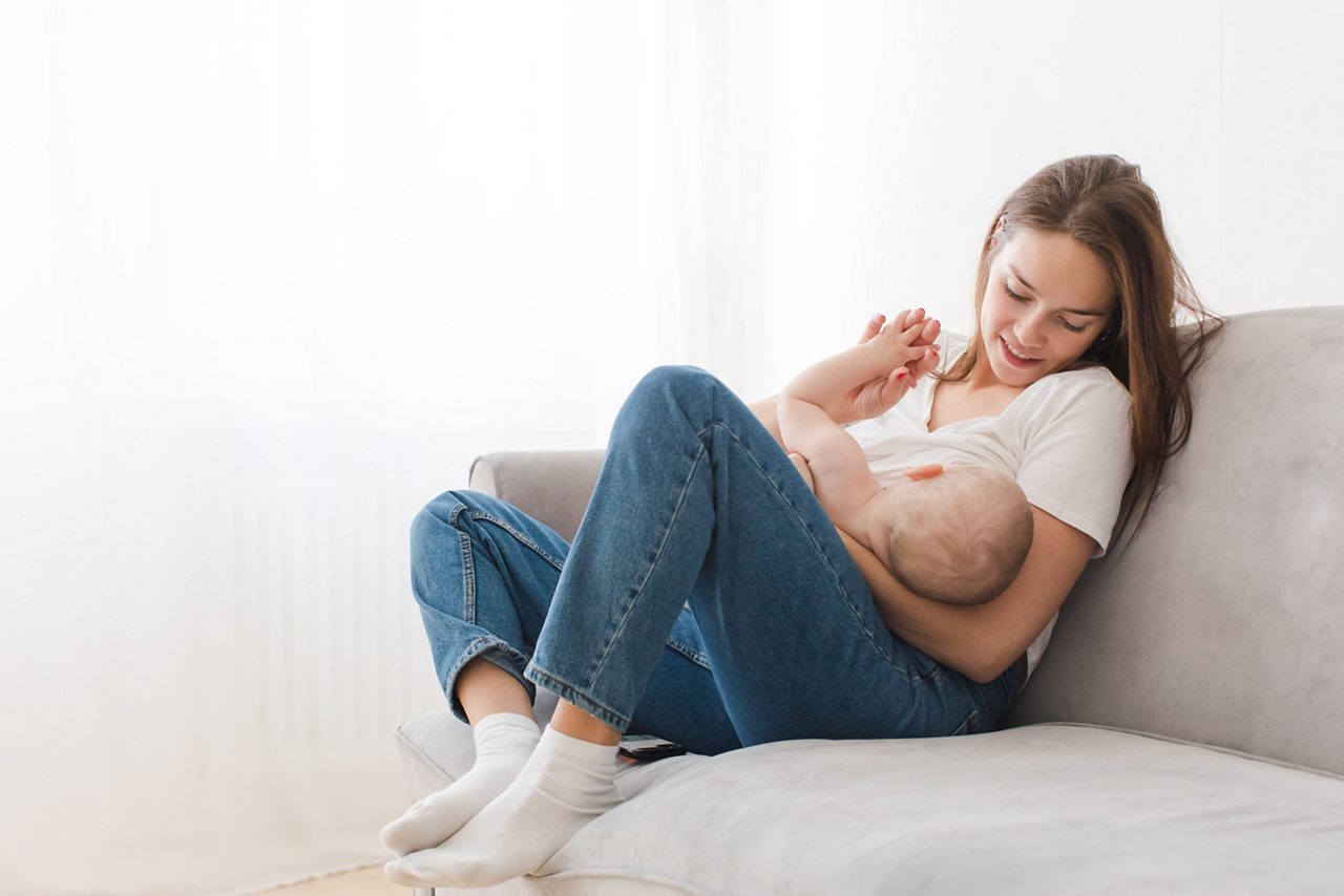 Mother is breastfeeding her kid sitting against light window background. Mom is suckling baby boy at home getty images 936738854