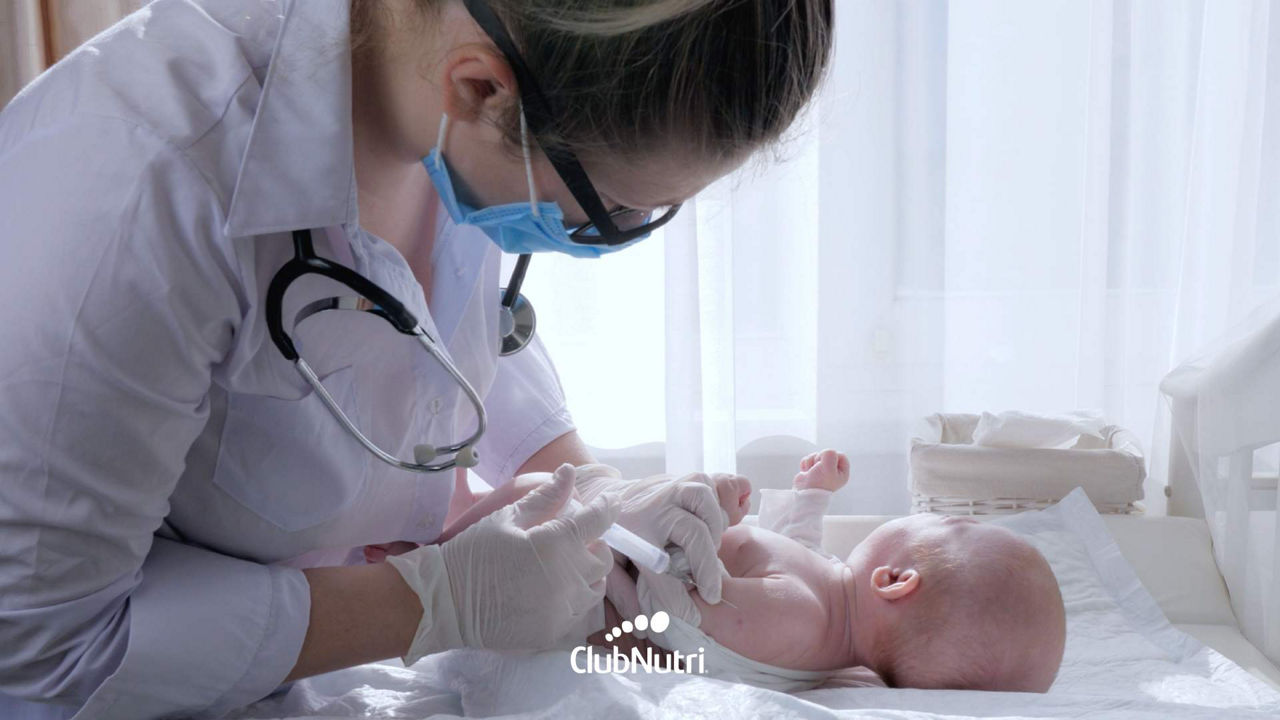 Médica poniéndole vacuna a bebé acostado