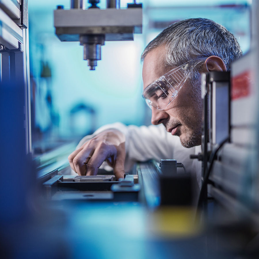 Image of a scientist with safety glasses looking at a sample.