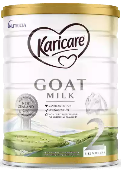 Front view of a Karicare goat milk formula tin with a gold lid. The label highlights gentle nutrition, key ingredients, and no added preservatives or artificial flavours. A New Zealand goat milk badge appears beside an illustration of a goat and a pastoral landscape with green hills and a windmill. The tin is marked for 6–12 months and shows a net weight of 900 g with a large number 2 indicating the stage.