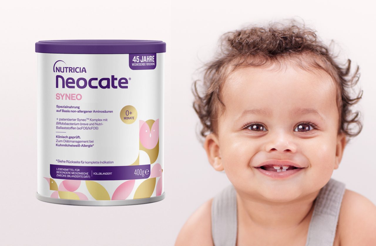 Eine Dose Nutricia Neocate Syneo Spezialnahrung steht neben einem lachenden Kleinkind vor hellem Hintergrund.