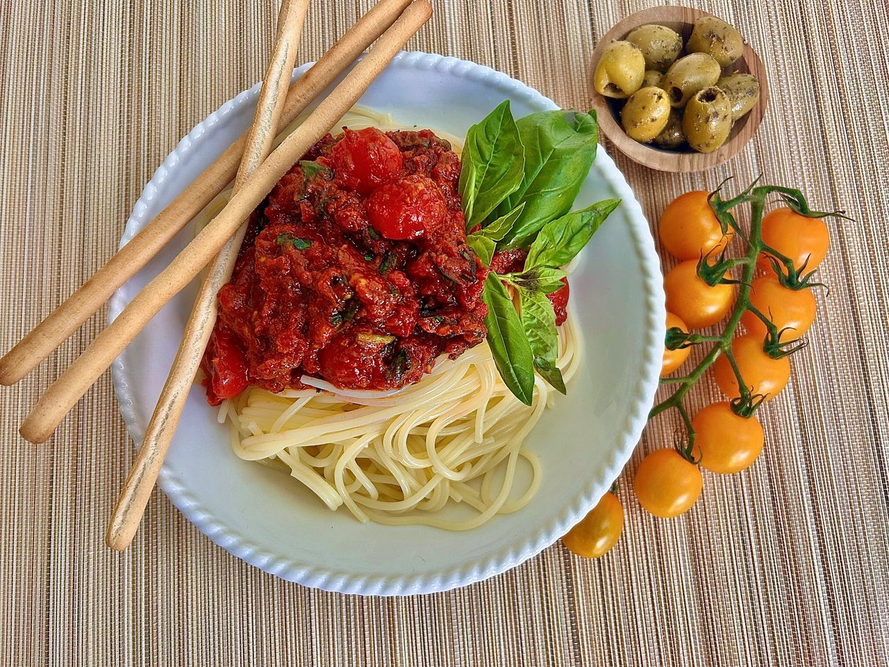 Person cutting cucumber on a wooden cutting board with fresh vegetables nearby.