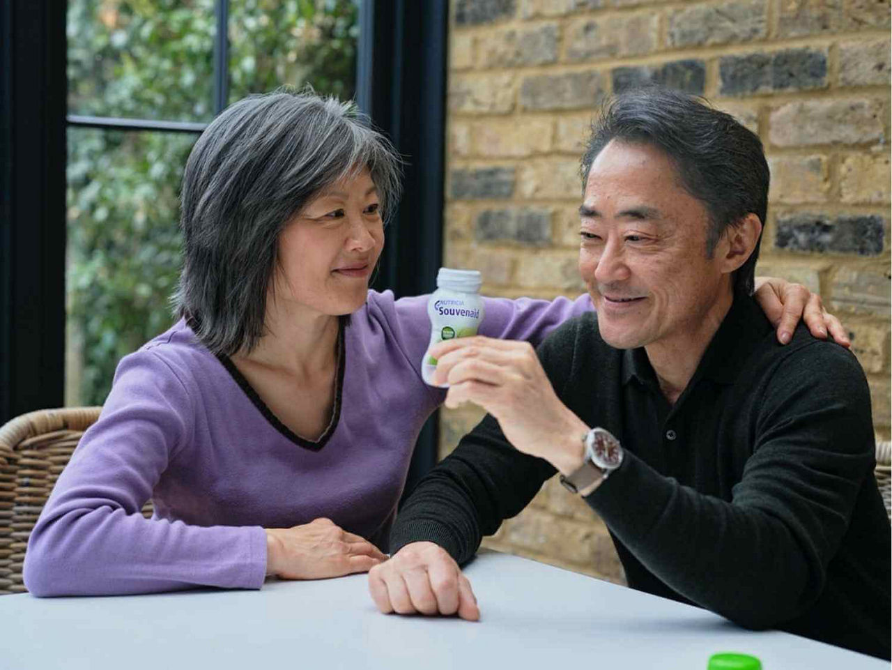 Man and woman sitting a table drinking souvenaid