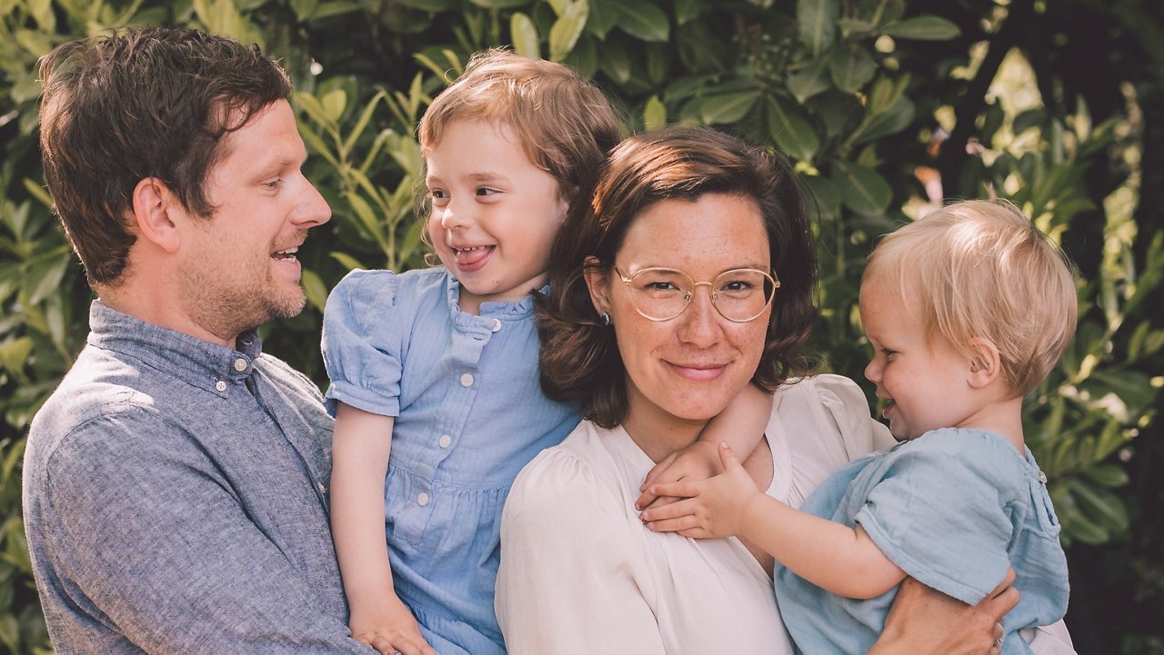 een gezin van vier waarbij de ouders elk één kind vasthouden