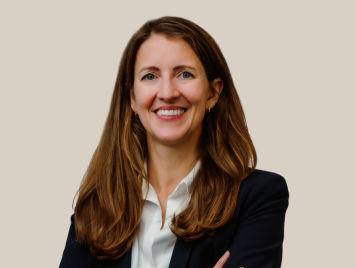 Marjolein de Koing, Vice President, Quality and Food Safety at Danone Canada, smiling woman and a warm expression in his portrait. She wears a black blazer over a white shirt and has a long dark hair.