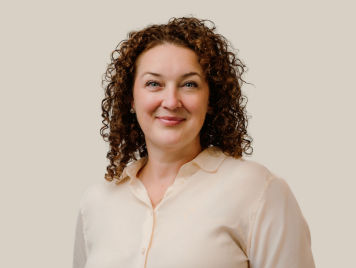 Mélanie Lebel, Senior Vice President of Human Resources at Danone Canada, smiling at her portrait. She wears a tan shirt and has medium-length red curly hair.