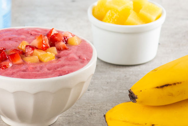 Un tazón lleno de un batido cremoso de frutas hecho con plátanos y fresas, ofreciendo una opción nutritiva y sabrosa
