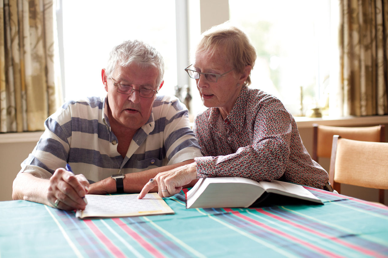 Elderly couple sitting at a table and writting on a paper