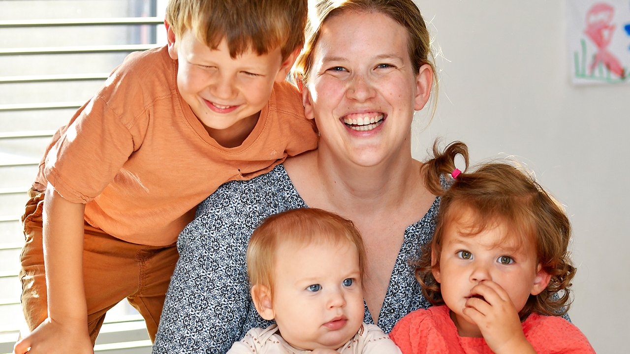 Een moeder zit aan tafel en houdt haar drie kinderen dicht bij zich. 