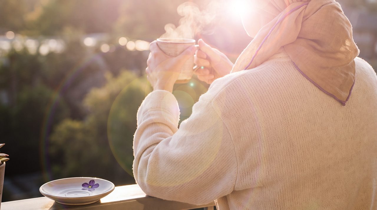 AI generated image of female cancer patient drinking coffee on the terrace.