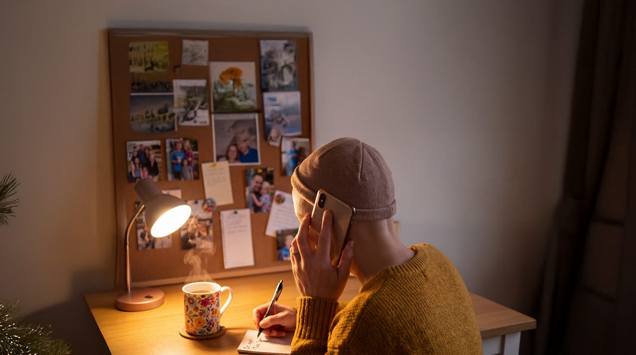 AI generated image of female cancer patient taking a mobile call with notepad.