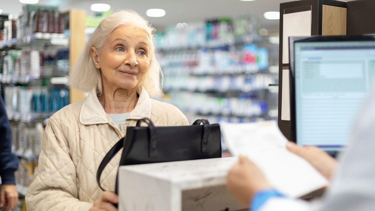Oudere vrouw aan de balie van een apotheek
