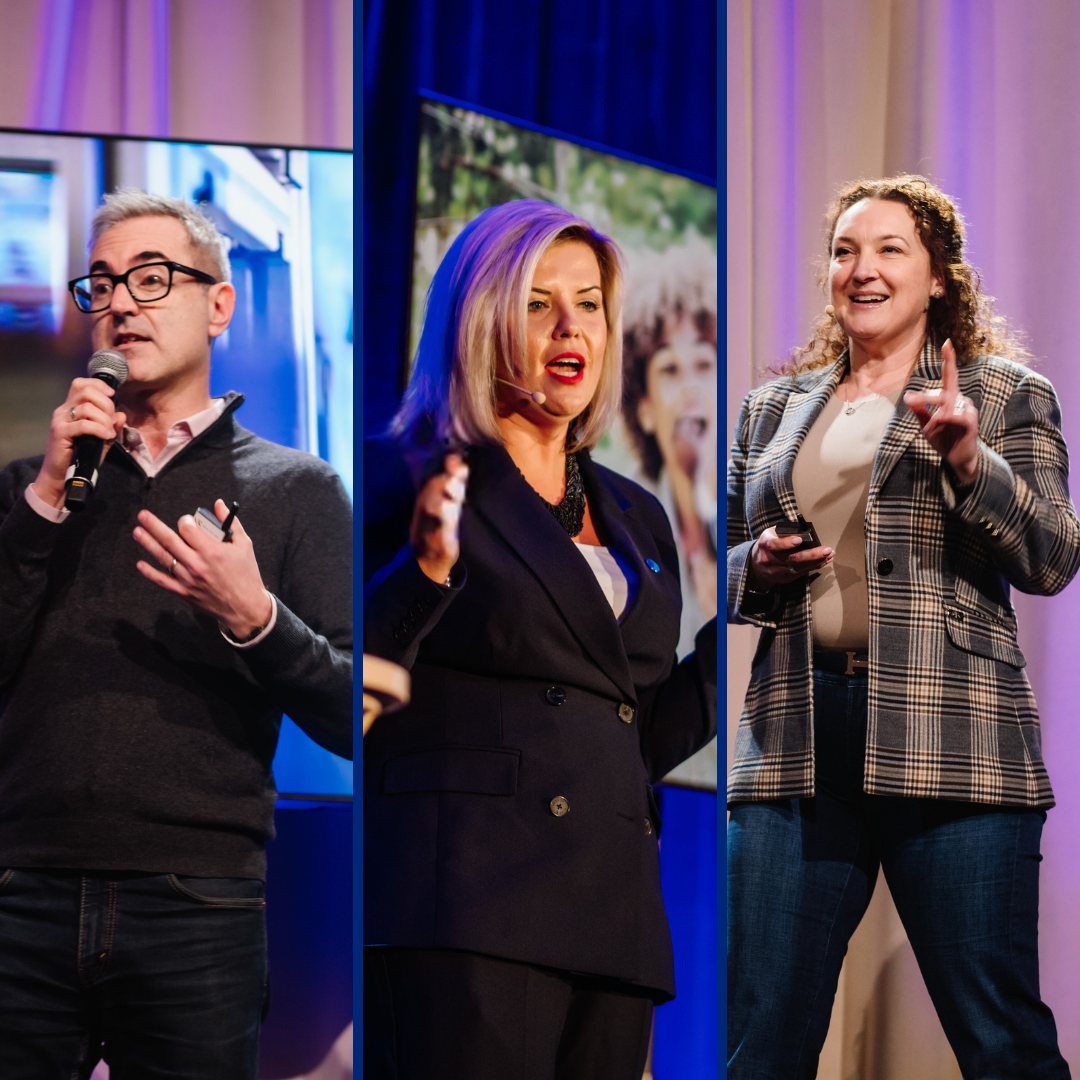 Three Danone Canada leaders stand on stage speaking at an event. From left to right: a man in a black blazer with short, grey straight hair (Frederic Guichard), a woman black blazer and blonde hair (Natalie Holloway), and a man with black blazer and a shaved head (Iannick Melancon). They're all wearing a microphone close to their mouth.