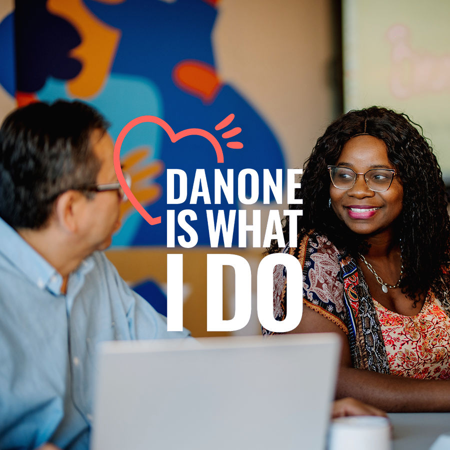 Two Danone Canada employees collaborate on a project using a laptop, embodying the company's culture statement: 'Danone is what I do.'