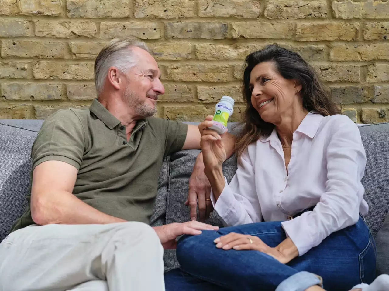 A man and woman sitting on a couch drinking Souvenaid 