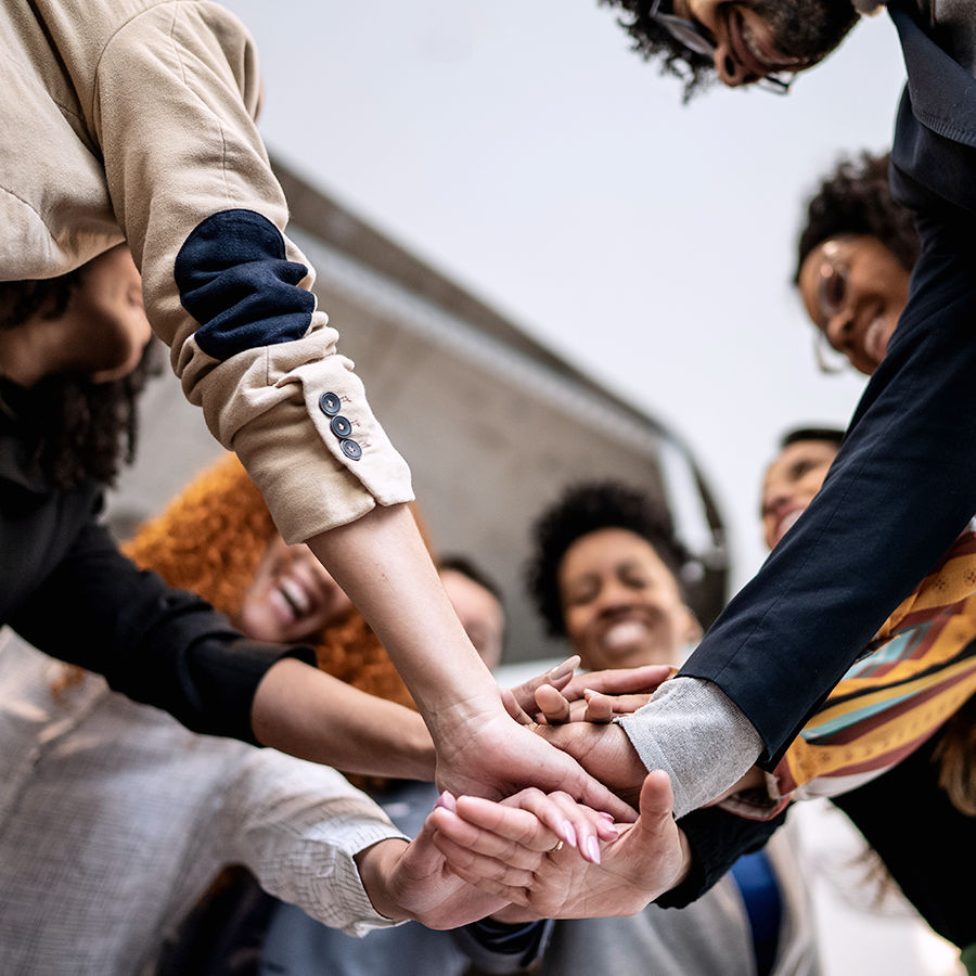 A diverse group of people joins hands in a circle.