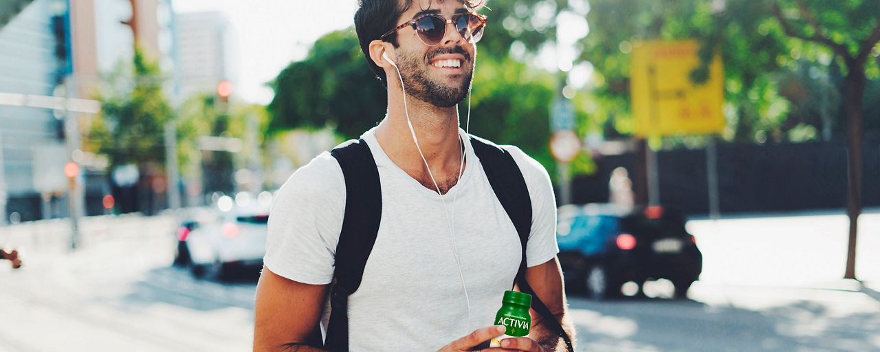 Ragazzo creativo in strada beve Activia