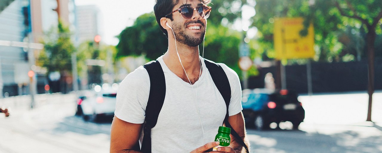 Ragazzo creativo in strada beve Activia