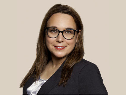 Isabelle Rayle-Doiron, Senior Vice President, General Secretary at Danone Canada, wears a black blazer and a confident expression, her smile accented by bold-framed glasses. She has long straight hair.