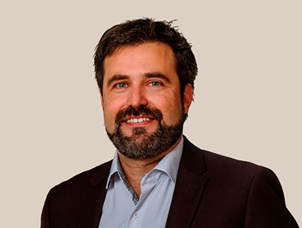 Pierre Morin, Vice President of Research & Innovation at Danone Canada, smiling and wearing a black blazer over a light blue dress shirt. He has a dark beard and short hair.