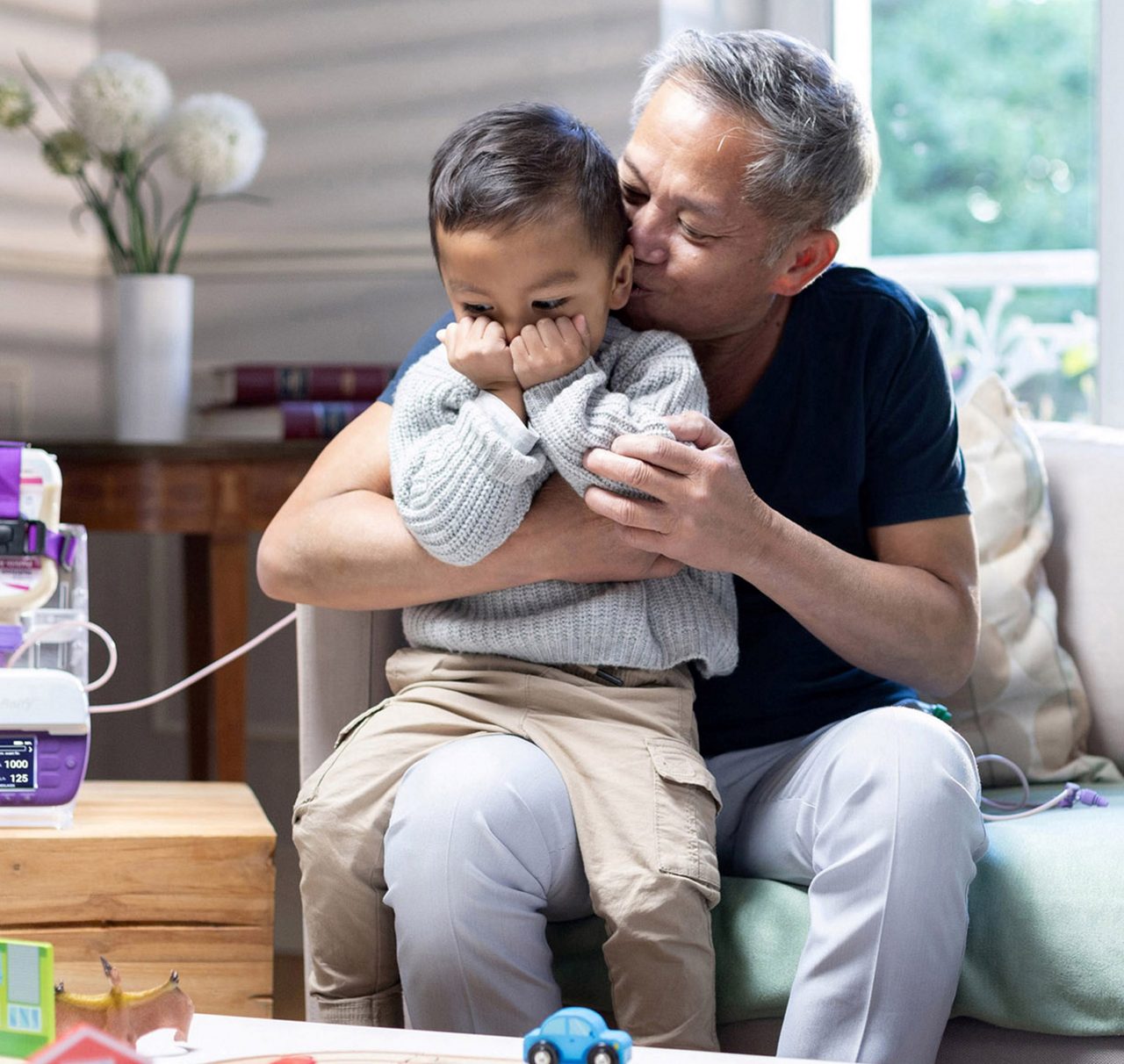 A father holds his son while tube feeding