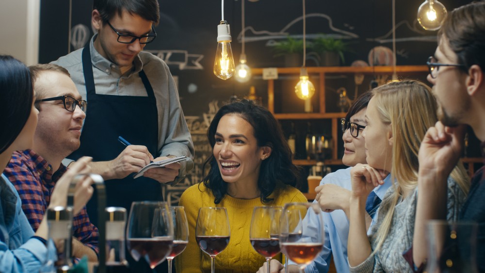 In the Bar/ Restaurant Waiter Takes Order From a Diverse Group of Friends. Beautiful People Drink Wine and Have Good Time in this Stylish Place.; Shutterstock ID 1031029918; Business Division: Advanced Medical Nutrition; Business Unit: Benelux; Name: Danique van der Tas