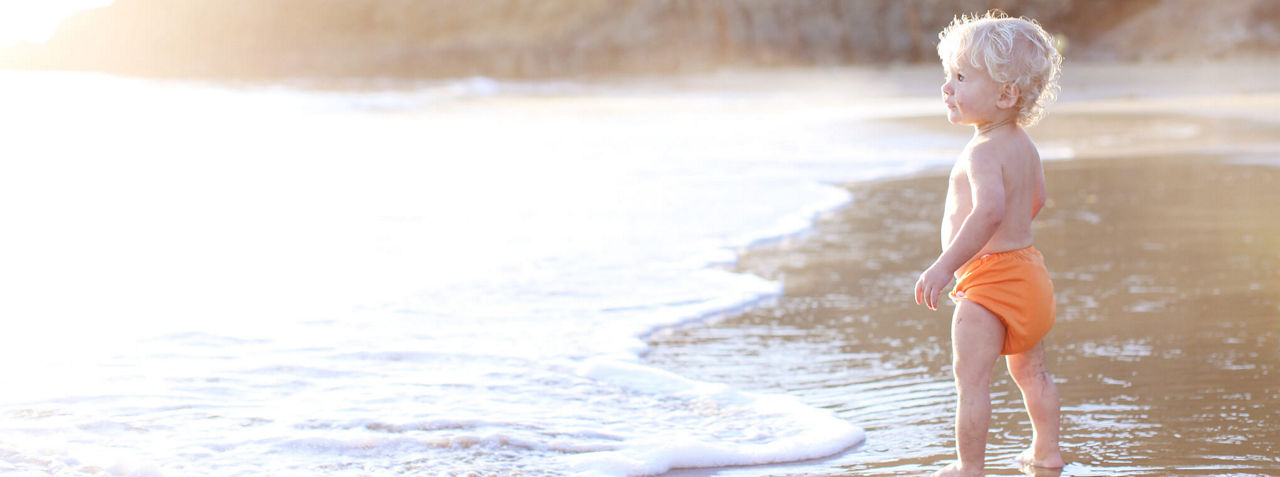 Baby with cloth nappies on the beach
