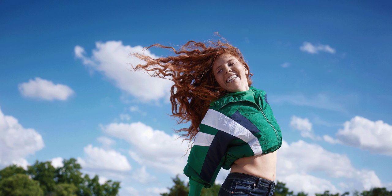Junge Frau mit Rollschuhen springt in die Höhe