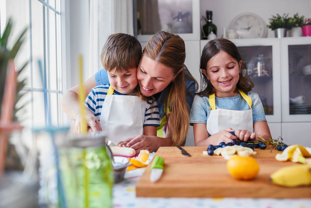 Cute kids with mother preparing a healthy fruit snack in kitchen ; Shutterstock ID 737100493; purchase_order: -; job: -; client: -; other: -