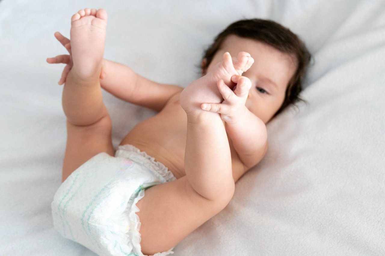 Baby mit Windeldermatitis liegt auf dem Bett