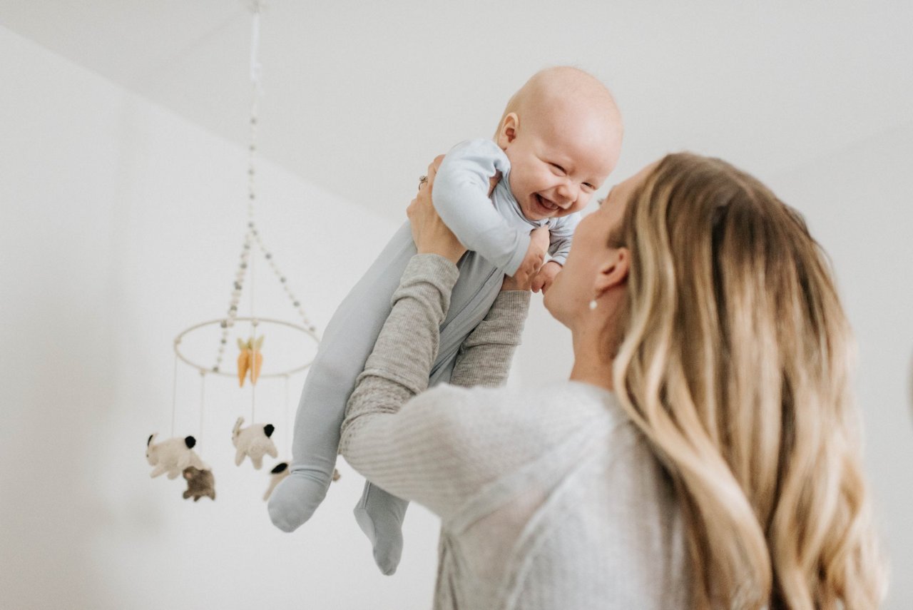 Mama hält lachendes Baby mit Schluckauf