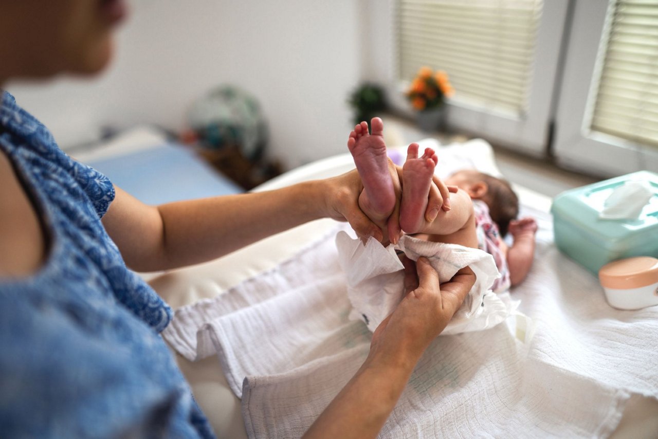 Mama wechselt Baby die Windel nach Stuhlgang
