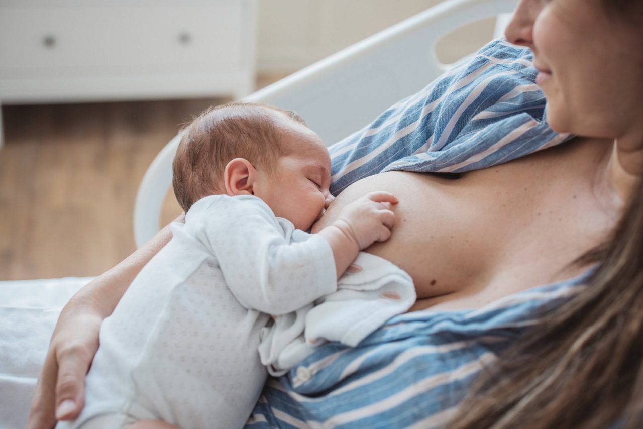 Frische Mutter stillt Baby nach Milcheinschuss im Wochenbett