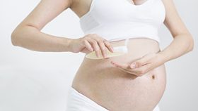Schwangere cremt Babybauch mit Creme Lotion ein