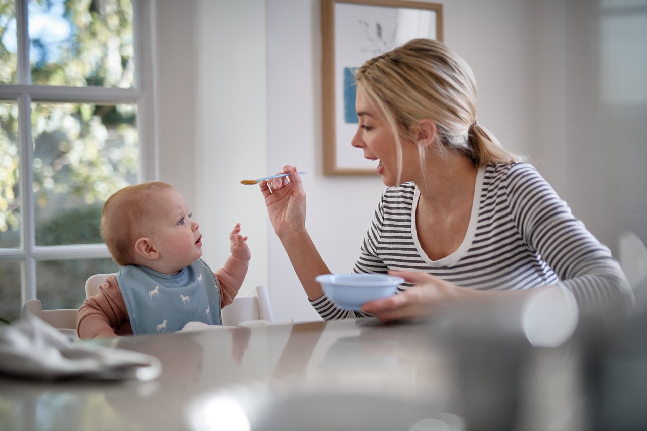 Mutter füttert Baby mit Beikost